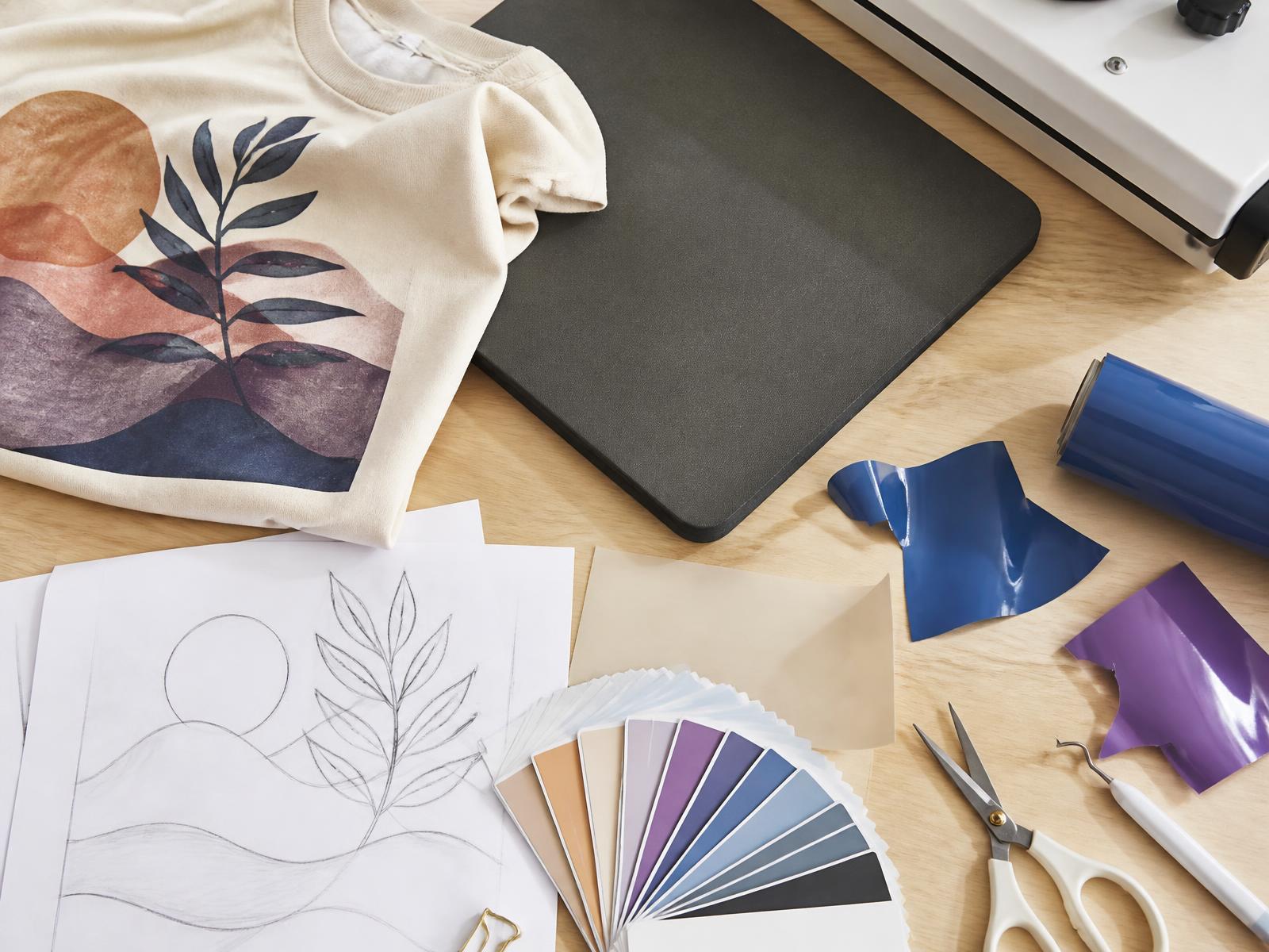 Vinyl, heat press, and finished custom pieces in the Qacee's Creations studio